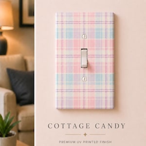 May include: A rectangular light switch wall plate featuring a pastel plaid pattern in shades of pink, light blue, and lavender. The plate has a central toggle switch and two silver screws, with the text COTTAGE CANDY printed below it.