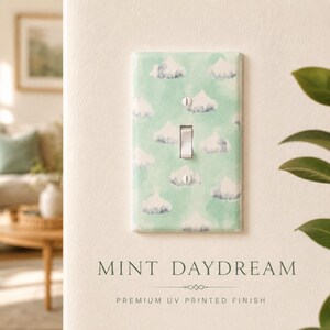 May include: A rectangular light switch cover plate featuring a repeating pattern of white and grey watercolor-style clouds on a soft mint green background. The plate includes a central toggle switch cutout and two silver mounting screws.