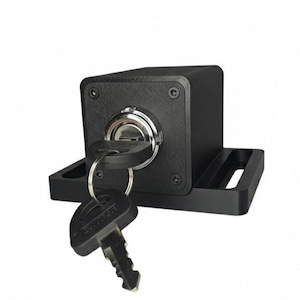 May include: A black, rectangular lock with a key inserted and another key hanging below. The lock has a silver keyhole and is mounted on a black base with slots. The keys are black with a silver key ring.