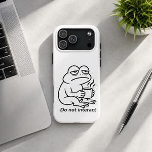 Könnte beinhalten: Weißes Handycase mit einer schwarz-weißen Illustration eines Frosches, der eine Kaffeetasse hält, und dem Text "Do not interact". Das Case hat einen Kameraausschnitt und schwarze Seitentasten.