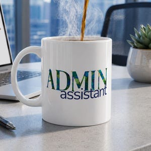 May include: A white ceramic mug with the words "ADMIN assistant" printed in blue and green floral lettering. The mug is filled with hot coffee, and steam rises from the top. A laptop, pen, and succulent plant are in the background.