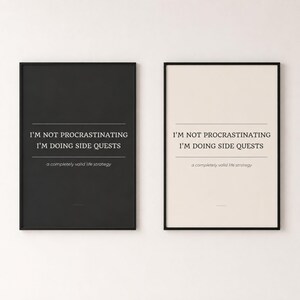 May include: Two rectangular wall art prints in black frames. One print has a black background with white text, and the other has a cream background with black text. Both feature the words: I'M NOT PROCRASTINATING I'M DOING SIDE QUESTS a completely valid life strategy.