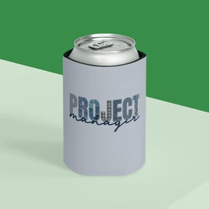 May include: A light blue can cooler with the words "PROJECT manager" in a mix of blue patterned fonts. A silver can sits inside the cooler, against a green and white background.