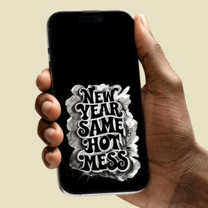 Könnte beinhalten: Ein schwarzes Smartphone zeigt den Text "NEW YEAR SAME HOT MESS" in einer stilisierten, wirbelnden Schriftart. Der Text ist weiß und grau auf schwarzem Hintergrund. Das Telefon wird in einer Hand gehalten.
