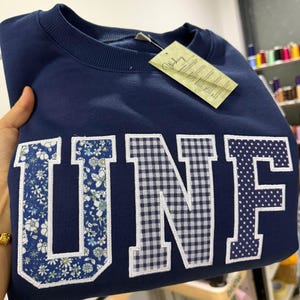 Op de afbeelding: Een witte keramische mok met een zwart handvat en de tekst "But First, Coffee" in een zwarte, vette letter. De mok staat op een houten oppervlak.