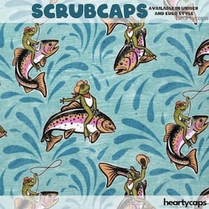 May include: Scrub caps with a whimsical design featuring frogs riding fish, set against a teal background with water splashes. The frogs wear cowboy hats and vests. The text "SCRUBCAPS" is at the top. The caps are available in unisex and Euro style.