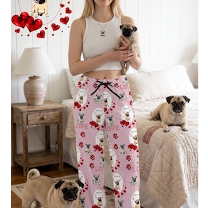 May include: Light pink pajama pants featuring a repeating pattern of pug dogs, red hearts, and red paw prints. The design includes the text I PUGGIN' LOVE YOU printed in small black letters within oval frames surrounding each illustrated pug dog.