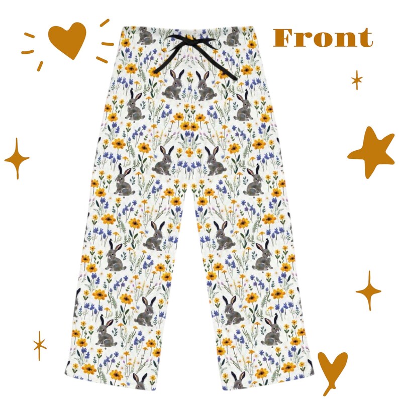 May include: White pajama pants with a floral and bunny rabbit pattern. The pants feature a drawstring waist and are covered in yellow flowers, blue wildflowers, and gray bunnies. The word "Front" is printed on the top right.