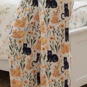 以下が含まれることがあります： 黒とオレンジの猫、黄色い花、緑の茎が全体にプリントされたクリーム色のパジャマパンツ。ゆったりとしたワイドレッグのシルエットで、ウエストはゴム仕様、柔らかく軽量な生地で作られています。