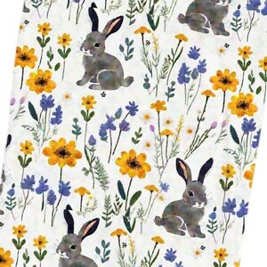 May include: A white fabric with a repeating pattern of gray rabbits, yellow and blue wildflowers, and green foliage. The design has a watercolor effect, creating a soft and whimsical aesthetic. This fabric is suitable for various craft projects.