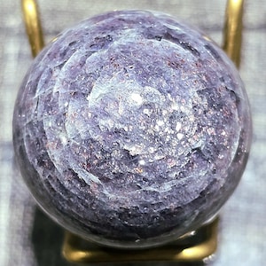 May include: A purple and silver sphere with a swirling pattern, displayed on a gold stand.