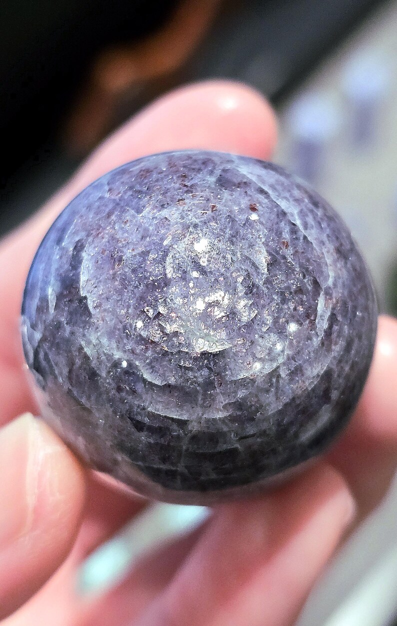 May include: A smooth, round, purple and grey gemstone with a swirling pattern.
