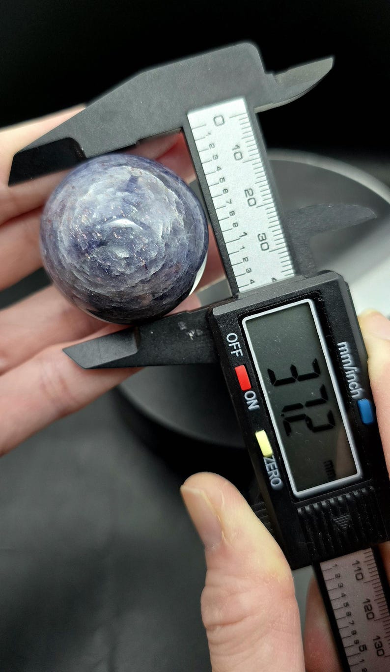 Puede incluir: Primer plano de una esfera de piedra preciosa azul y morada que se mide con un calibre digital. El calibre indica 37,2 mm.