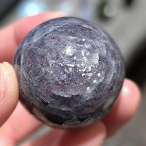 May include: A smooth, round, purple and gray gemstone sphere with a swirling pattern.
