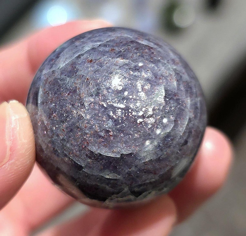 May include: A smooth, round, purple and gray gemstone sphere with a swirling pattern.