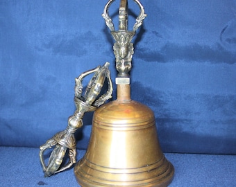 May include: A brass bell with a decorative handle, known as a "dorje" in Tibetan Buddhism. The bell is used in rituals and meditation.