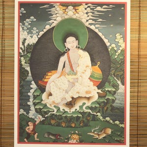 May include: A colorful painting depicting a deity seated on a throne with a green halo. The deity is holding a bowl and is surrounded by clouds and mountains. The painting is done in a traditional Tibetan style.