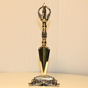 Peut inclure: Un poignard rituel en métal doré avec une poignée décorative et une lame pointue. Le poignard est monté sur un support décoratif avec des détails complexes.