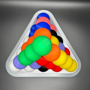 May include: A white triangle-shaped rack holds a pyramid of colorful balls. The balls are red, orange, yellow, green, blue, purple, white, and black.