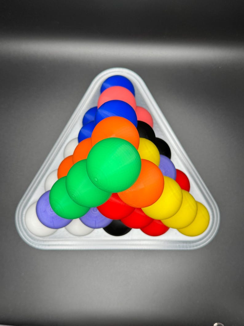 May include: A white triangle-shaped rack holds a pyramid of colorful balls. The balls are red, orange, yellow, green, blue, purple, white, and black.