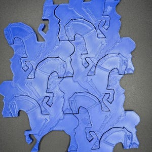May include: A blue jigsaw puzzle depicting a horse and rider in a repeating pattern. The pieces fit together to create a larger form. The design is a solid blue with a textured surface.