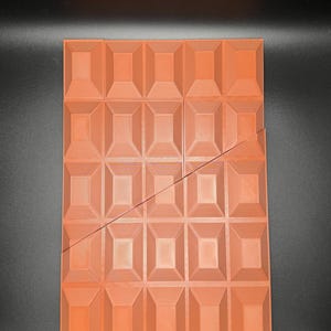 Op de afbeelding: Een rechthoekige, oranje-bruine chocolade vorm met een diagonale lijn in het midden. De vorm is verdeeld in 36 vierkanten, elk met een verhoogd, ruitvormig patroon.