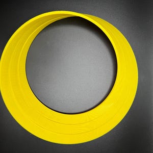 May include: A yellow plastic ring with three concentric circles. The ring is on a black background.