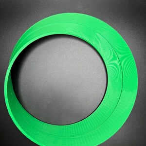 May include: A green plastic ring with a textured surface. The ring is approximately 25 cm in diameter.