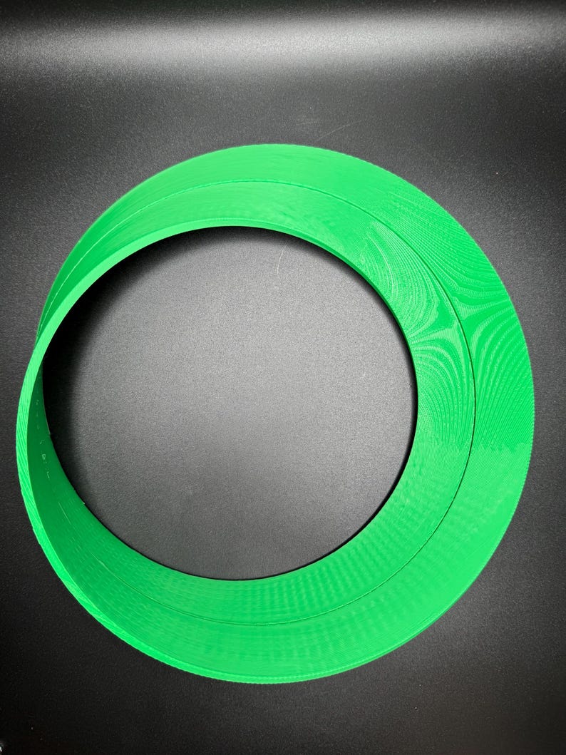 May include: A green plastic ring with a textured surface. The ring is approximately 25 cm in diameter.