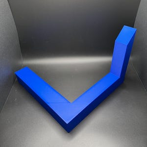K&ouml;nnte beinhalten: Ein blaues, L-f&ouml;rmiges, geometrisches Regal aus Kunststoff. Das Regal ist f&uuml;r die Wandmontage konzipiert.