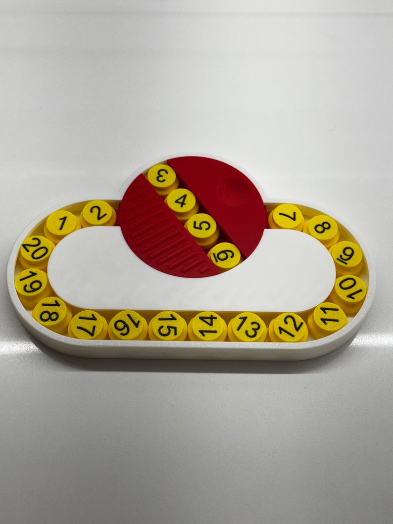 May include: A white plastic toy with a red and white circular piece in the center. The toy has a ring of yellow circles with numbers 1 through 20 around the outside.