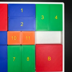 May include: A white tray with colorful tiles numbered 1 through 11 and the letter B. The tiles are arranged in a grid pattern.