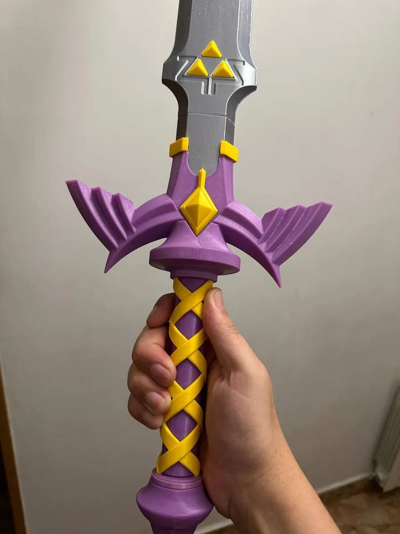 May include: A purple and yellow 3D printed sword with a triangular design on the blade and a braided handle.