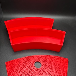 May include: Two red, curved, plastic trays with a red, curved, plastic lid with a hole in the center.