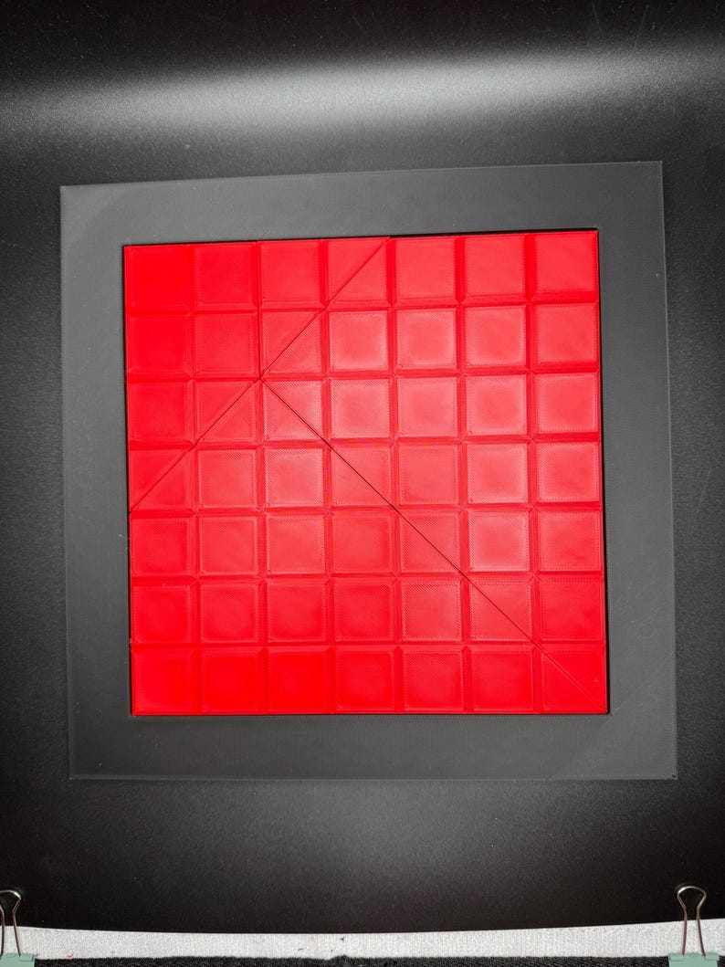 K&ouml;nnte beinhalten: Ein rotes quadratisches Puzzle mit einer diagonalen Linie, die es in zwei Dreiecke teilt. Das Puzzle besteht aus kleineren Quadraten.