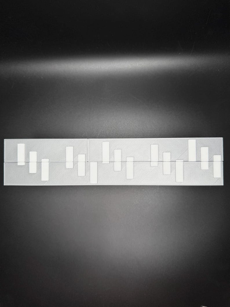 May include: A white plastic ruler with black markings. The ruler is divided into sections with different lengths. The ruler is a useful tool for measuring and drawing.