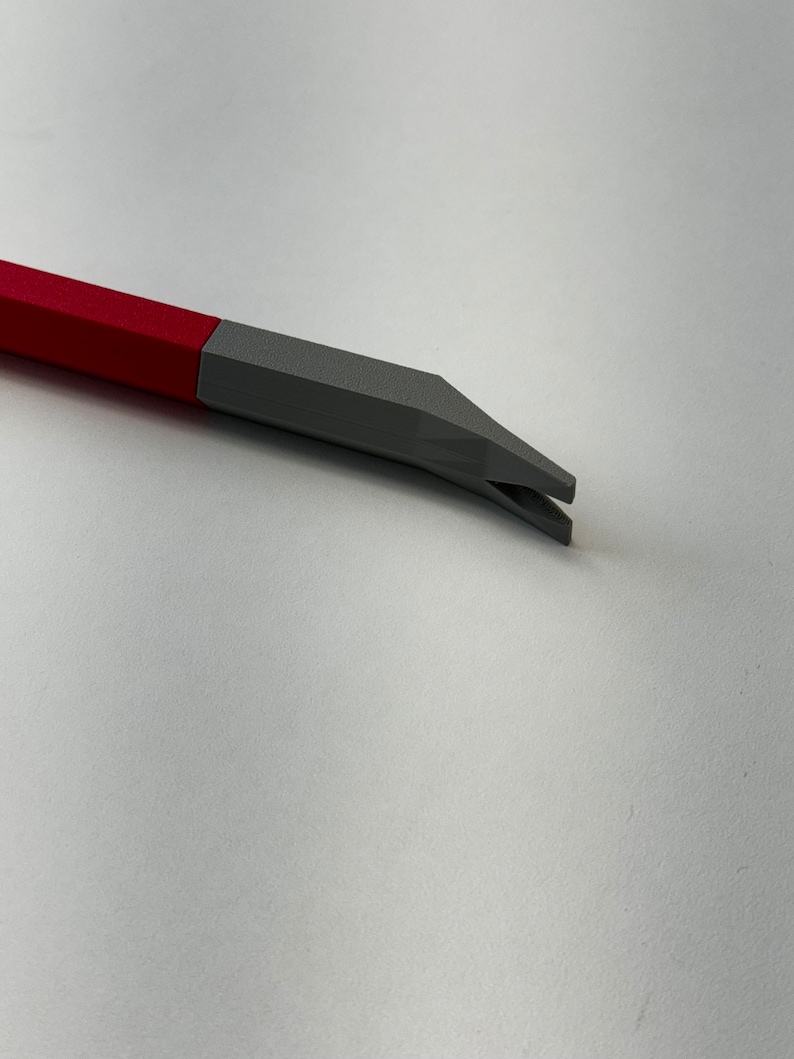 May include: A red and gray plastic tool with a pointed end and a small opening. The tool is designed for prying or lifting.