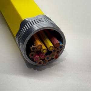 May include: A yellow pencil case with a gray cap, filled with a variety of colored pencils. The pencils are arranged in a circular pattern, with the tips of the pencils facing outwards.