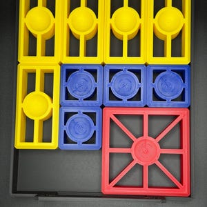 Puede incluir: Un conjunto de nueve fichas de pl&aacute;stico de colores con diferentes formas y dise&ntilde;os. Las fichas son amarillas, azules y rojas. Las fichas est&aacute;n dispuestas en un patr&oacute;n de cuadr&iacute;cula.
