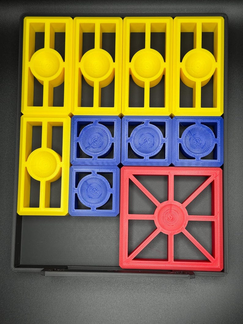 Puede incluir: Un conjunto de nueve fichas de pl&aacute;stico de colores con diferentes formas y dise&ntilde;os. Las fichas son amarillas, azules y rojas. Las fichas est&aacute;n dispuestas en un patr&oacute;n de cuadr&iacute;cula.