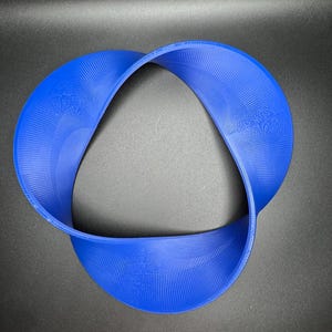 May include: A blue, 3D printed, Mobius strip sculpture. The strip is twisted and folded to create a continuous loop.