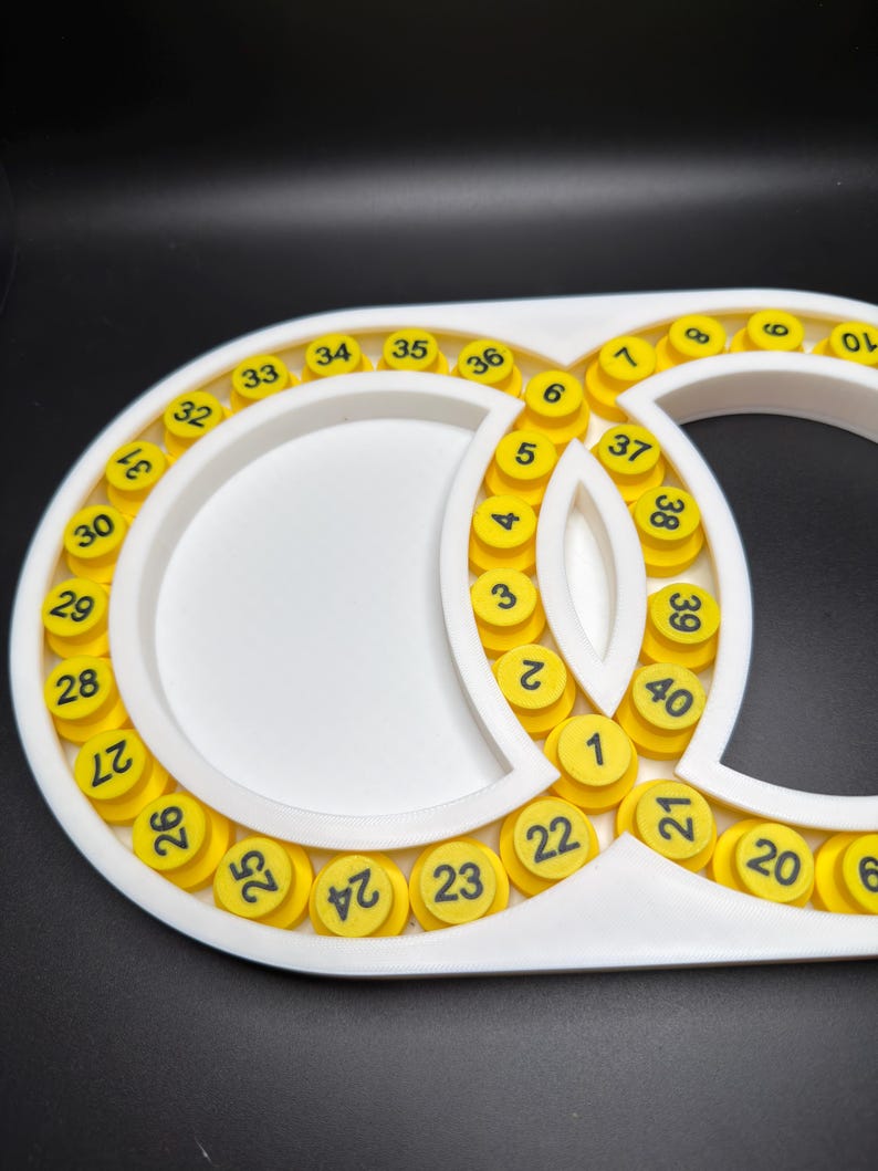 May include: A white plastic organiser tray featuring a figure-eight shape with two circular compartments. The tray is lined with forty small, yellow, cylindrical pegs, each marked with a black number ranging sequentially from one to forty.