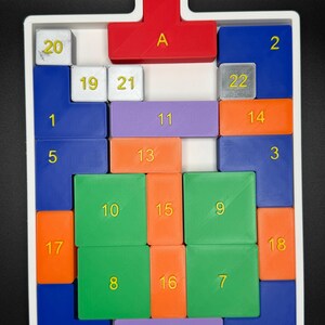 Op de afbeelding: Een wit dienblad met een rode, paarse, blauwe, groene en oranje puzzel. De puzzelstukken zijn genummerd van 1 tot 22 en gelabeld met de letter "A".