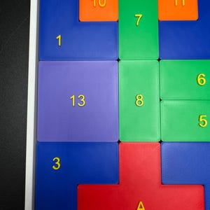 May include: A colorful puzzle with numbered tiles in various colors, including blue, green, red, orange, and purple. The numbers on the tiles range from 1 to 13, with the letter "A" replacing the number 14.