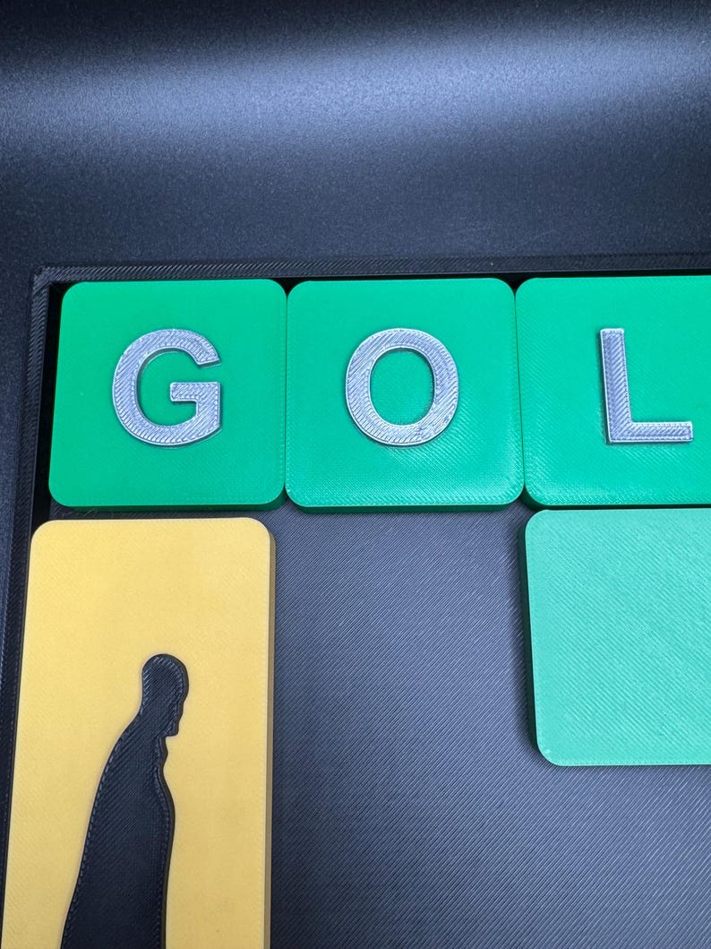 May include: Green tiles with the letters G, O, and L in white on them. The tiles are on a black surface.
