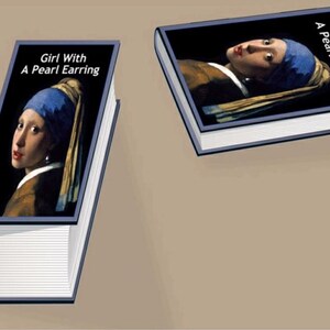 Op de afbeelding: Twee boeken met de omslag van Johannes Vermeer's "Meisje met de parel". De titel staat in het wit op een zwarte achtergrond. De afbeelding op de omslag toont het meisje met een blauwe hoofddoek en een parel oorbellen.