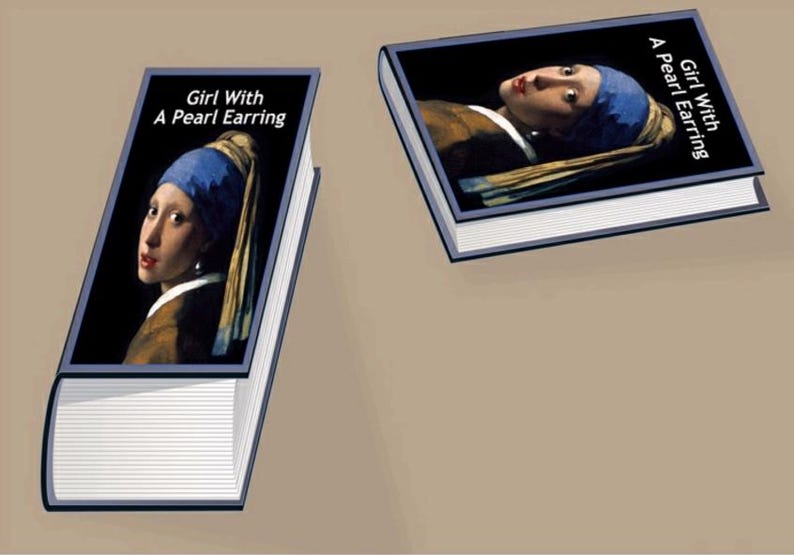 Op de afbeelding: Twee boeken met de omslag van Johannes Vermeer's "Meisje met de parel". De titel staat in het wit op een zwarte achtergrond. De afbeelding op de omslag toont het meisje met een blauwe hoofddoek en een parel oorbellen.