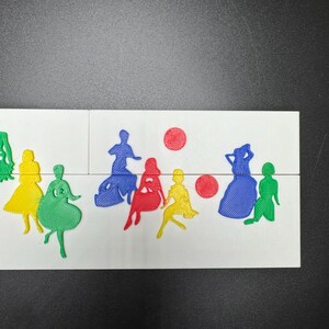 May include: A set of colorful, 3D printed figures of people, including a yellow, green, blue, and red figure. There are also two red circles in the background.