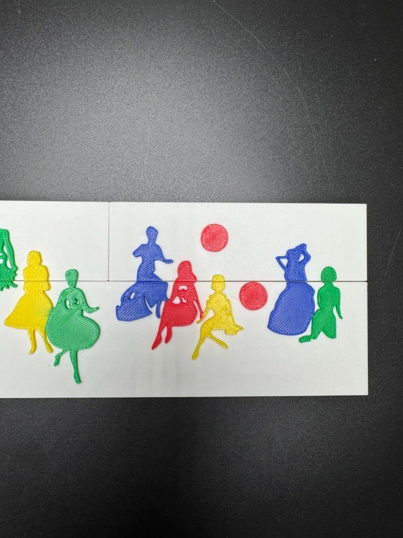 May include: A set of colorful, 3D printed figures of people, including a yellow, green, blue, and red figure. There are also two red circles in the background.