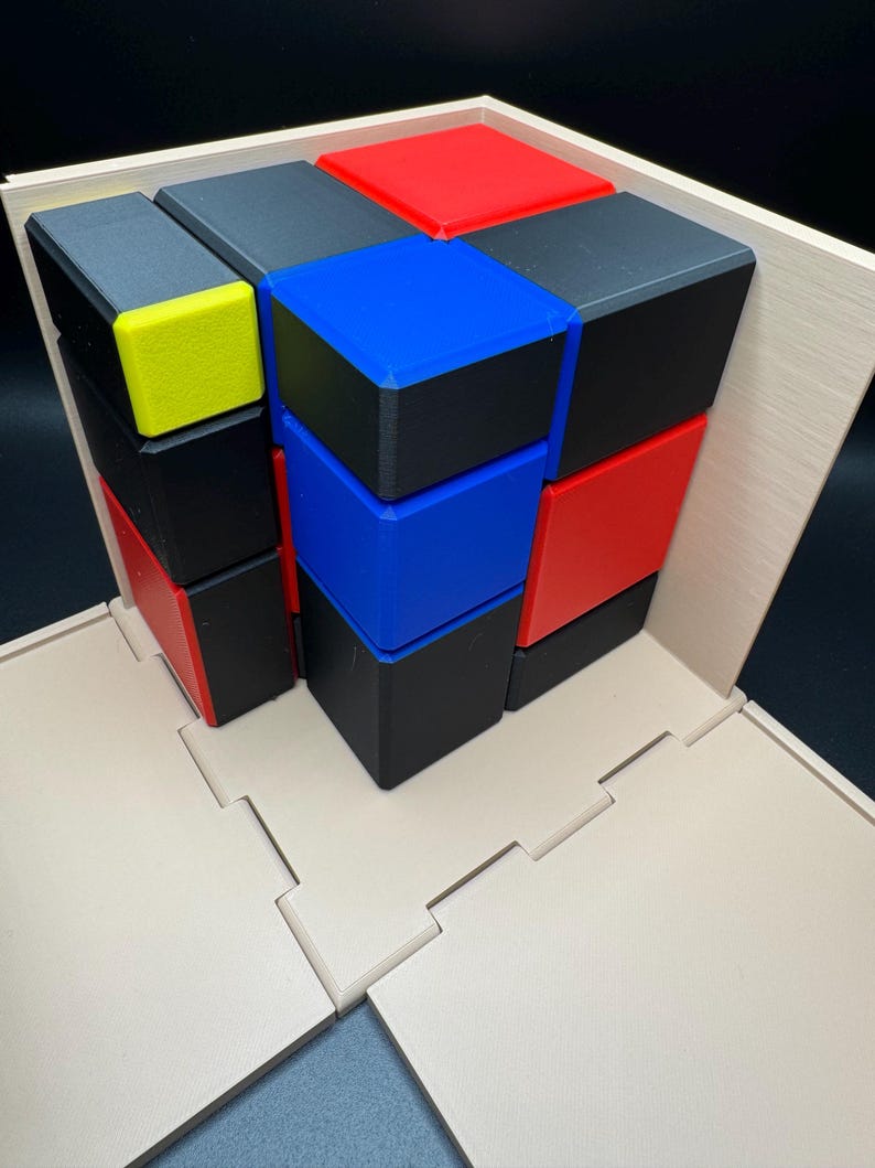 May include: A 3D puzzle with a wooden base and nine colourful blocks. The blocks are red, blue, black, and yellow. The puzzle is assembled in a tower shape.